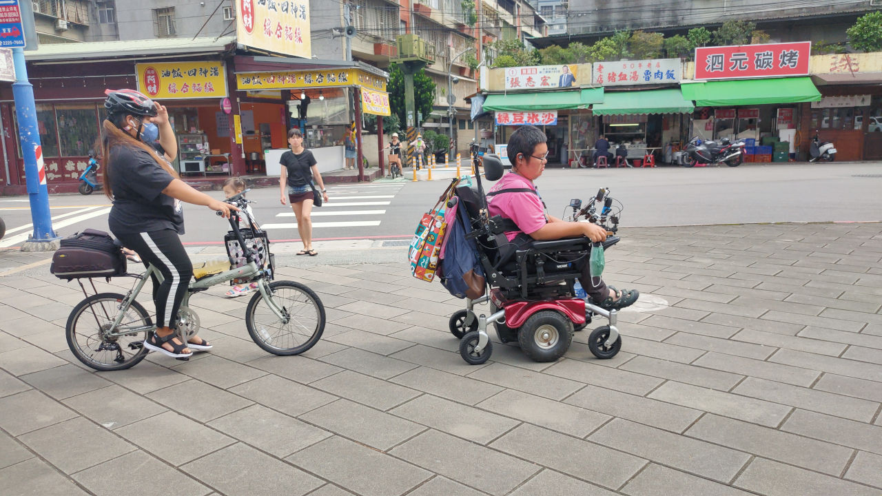 太太騎腳踏車載著兒子潤潤跟著自學團的大隊，小齊由外傭莉亞騎腳踏車跟隨協助
