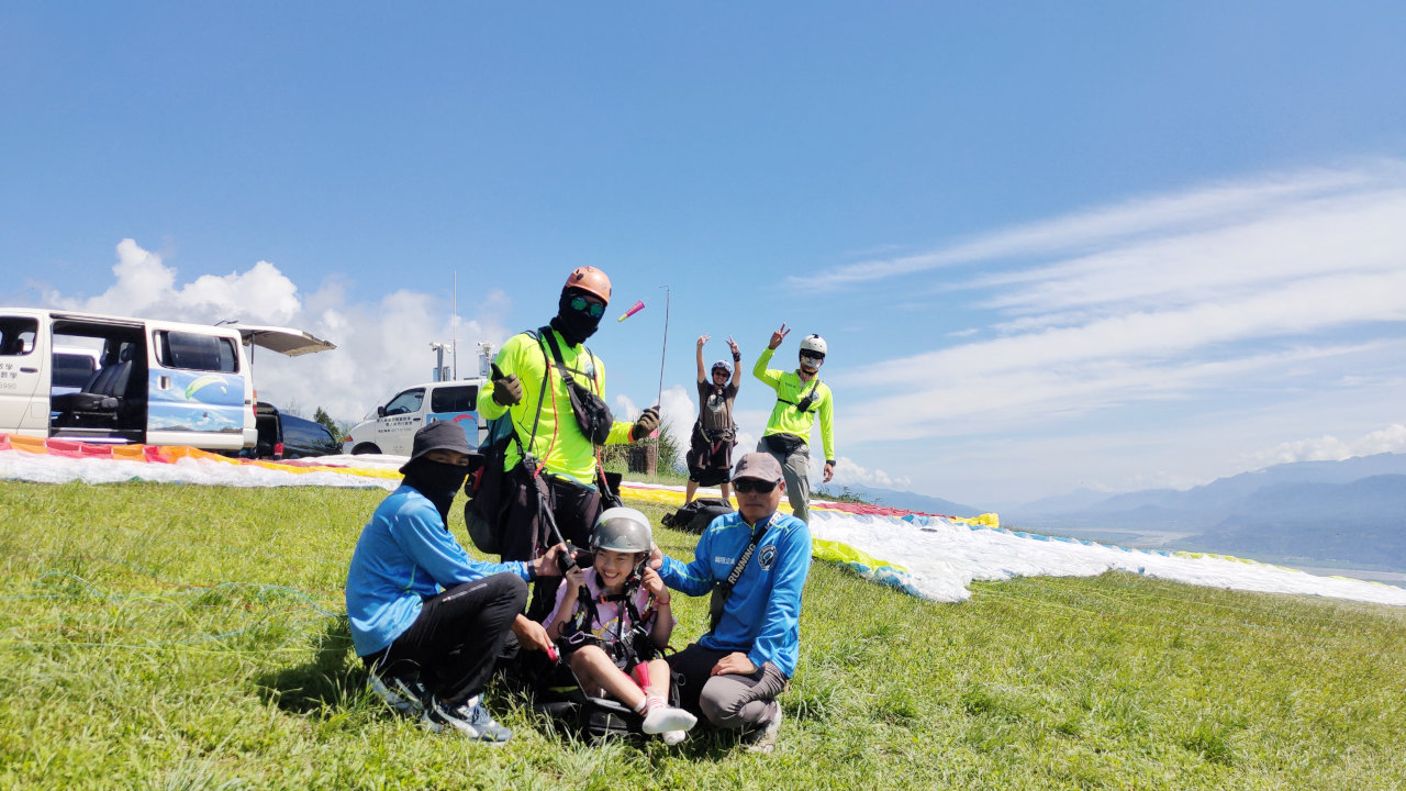 一位教練及兩位助飛員協助小米體驗飛行傘
